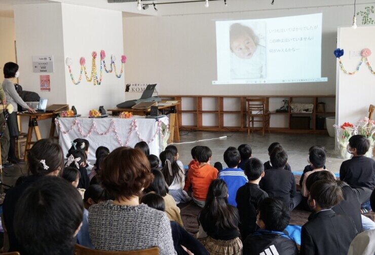 小学生の卒業生がスライドを見ている卒業式の光景