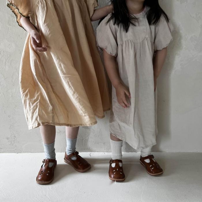 女の子2人がワンピースを着て、前を向いて立っている。胸より下の写真。